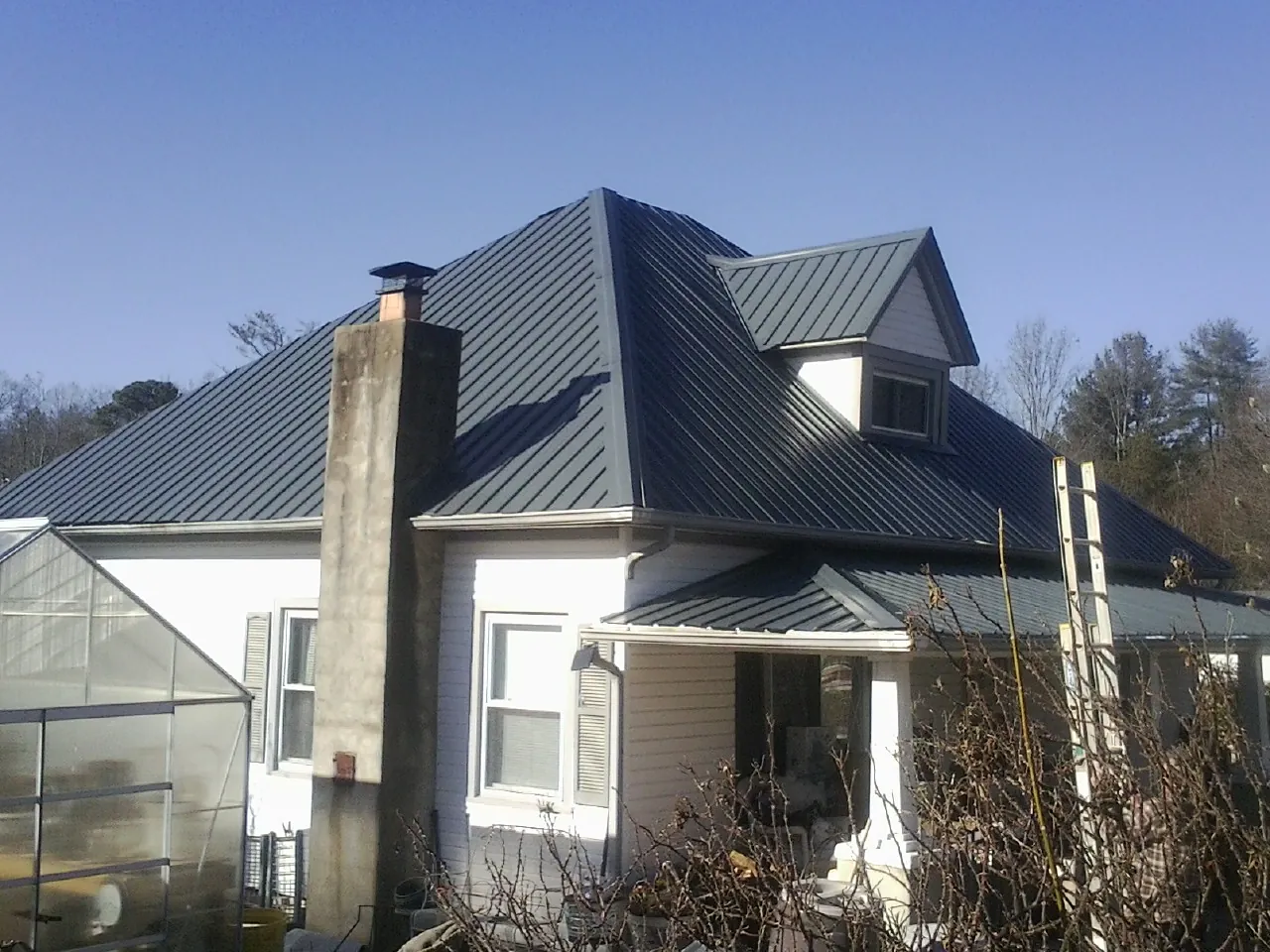 Dark blue standing seam metal roof on a white farmhouse with dormer — Slate & Tile Roof Repair by Roofing Brothers in Rosemount