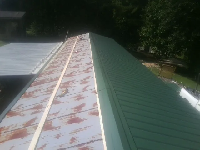 Old rusted panels beside newly installed green metal roofing — Wind Damage Roof Repair by Roofing Brothers in Rosemount