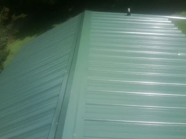 New green metal panels meeting at the ridge of a roof — Flat Roof Repair work by our crew in Rosemount