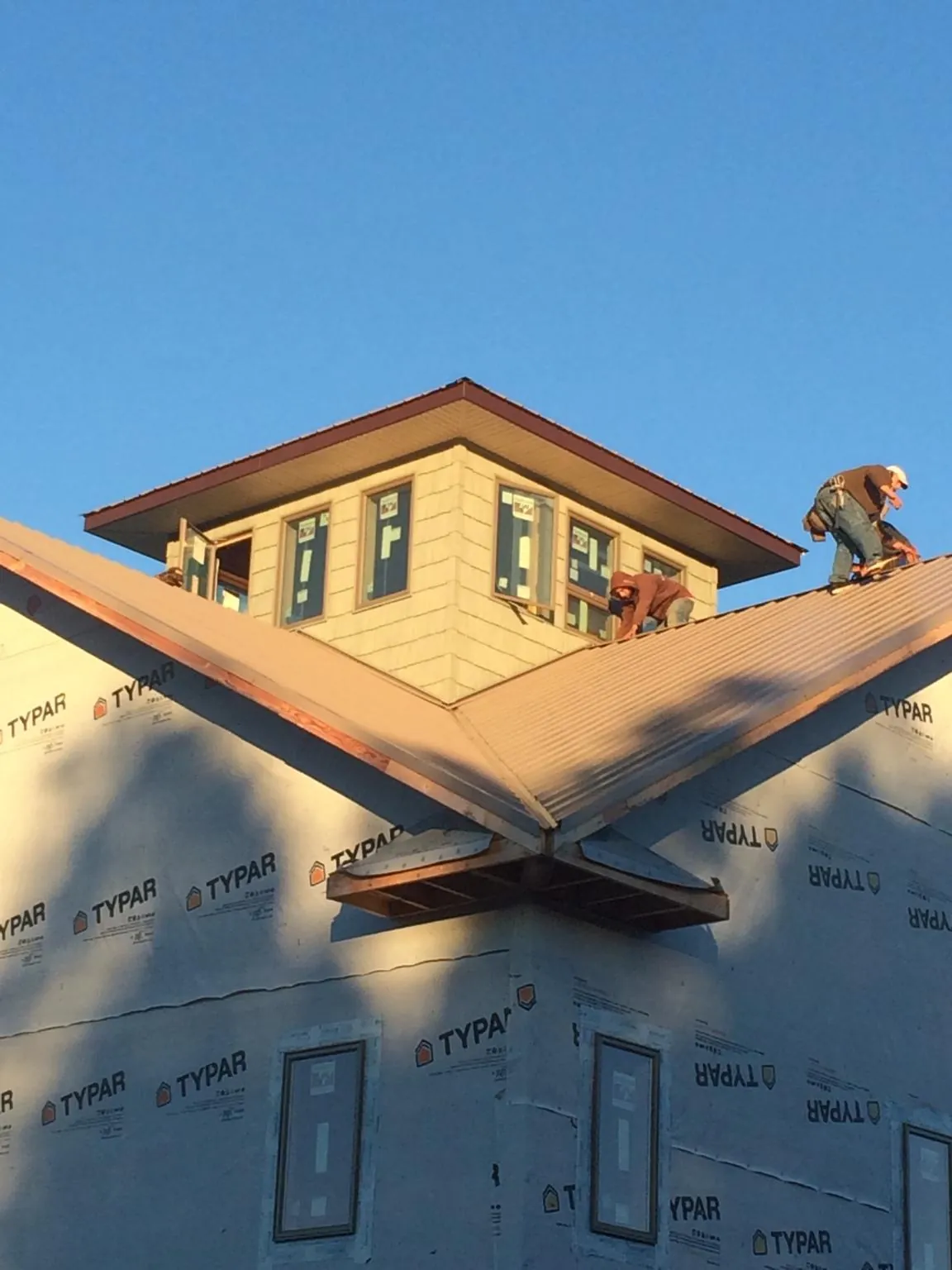 Roofers working around a rooftop cupola on a new metal roof at sunset — Roof Waterproofing in Rosemount by Roofing Brothers